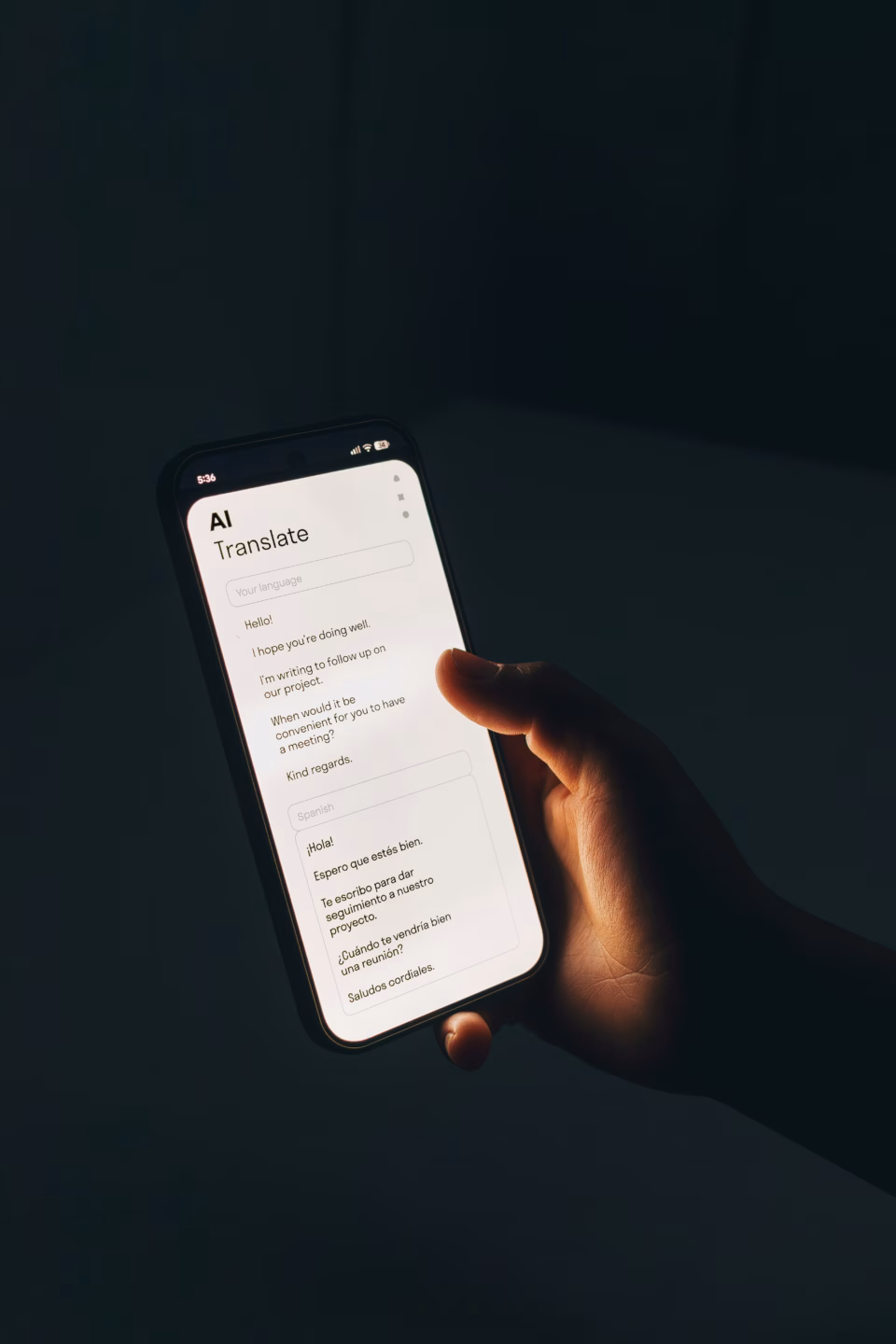 symbolbild für KI-gestützte Echtzeitübersetzung. Ein Smartphone in der Hand einer Person. Auf dem Bildschirm ist der Text "AI Translate" zu erkennen.